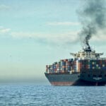 A plume of smoke rises from a cargo tanker at sea