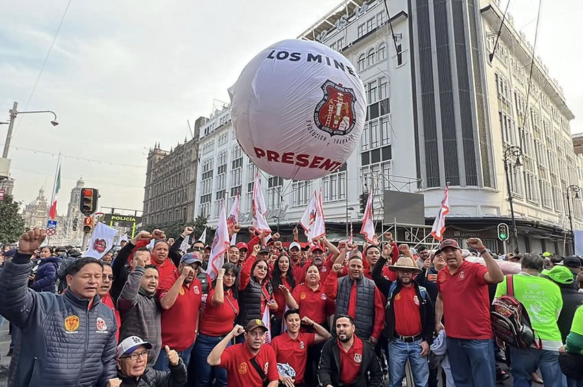 A group of union miners in red shirts raise their fists and flags at the December "4T" rally in Mexico City