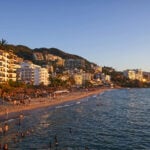 Tourists swim and lounge on the beach in front of Puerto Vallarta hotels and condos