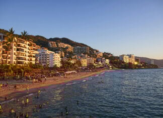 Tourists swim and lounge on the beach in front of Puerto Vallarta hotels and condos