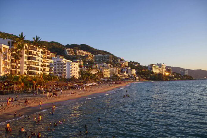 Tourists swim and lounge on the beach in front of Puerto Vallarta hotels and condos