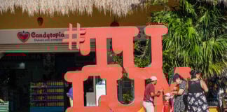 A family takes photos near a sculpture of the word #TULUM