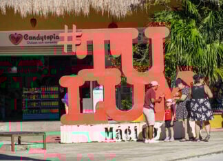 A family takes photos near a sculpture of the word #TULUM