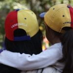 A woman and small girl hug wearing Venezuelan ball caps