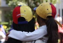 A woman and small girl hug wearing Venezuelan ball caps