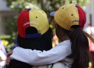 A woman and small girl hug wearing Venezuelan ball caps