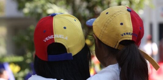 A woman and small girl hug wearing Venezuelan ball caps