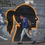 A man walks in front of a faded mural of the silhouette of President Claudia Sheinbaum, on Emiliano Zapata Street in Mexico City.