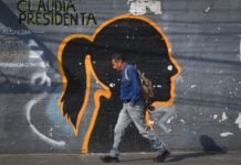 A man walks in front of a faded mural of the silhouette of President Claudia Sheinbaum, on Emiliano Zapata Street in Mexico City.