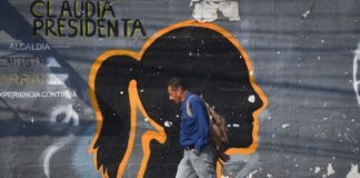 A man walks in front of a faded mural of the silhouette of President Claudia Sheinbaum, on Emiliano Zapata Street in Mexico City.