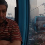 A man looks out over Mexico City from a public transport gondola