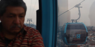 A man looks out over Mexico City from a public transport gondola