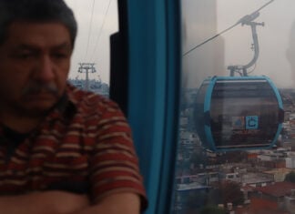 A man looks out over Mexico City from a public transport gondola