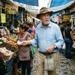 an elderly American expat with a shabby hat (but otherwise perfect clothes), looking confused as he shops at a horrible market in Mexico