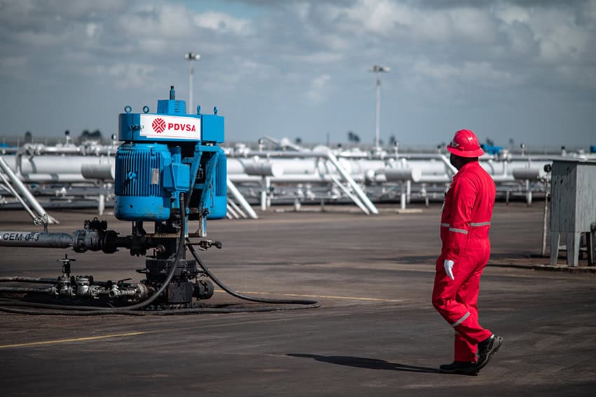 A worker walks by gas lines at a PDVSA Venezuela oil facility