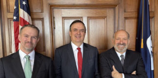 Marcelo Ebrard, Jamieson Greer and Howard Lutnick stand next to an American flag