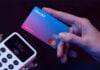 A hand holds a Revolut credit card next to a payment terminal