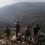 US soldiers look out over an arid valley