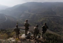 US soldiers look out over an arid valley