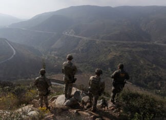 US soldiers look out over an arid valley
