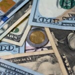 Dollar bills surround a one-peso coin