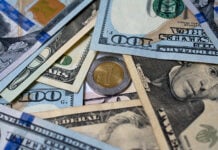 Dollar bills surround a one-peso coin