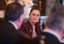 President Sheinbaum in focus, talking to a couple of men in business suits