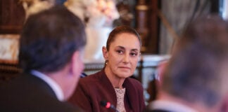 President Sheinbaum in focus, talking to a couple of men in business suits
