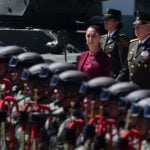 Sheinbaum and two Mexican generals observe a military band on Army Day in Puebla