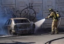 A firefighter extinguishes a burning car after violence following the death of El Mencho