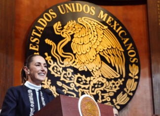 President Sheinbaum in front of a large seal reading Estados Unidos Mexicanos