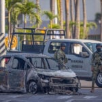 Mexican marines inspect a burned car in Puerto Vallarta