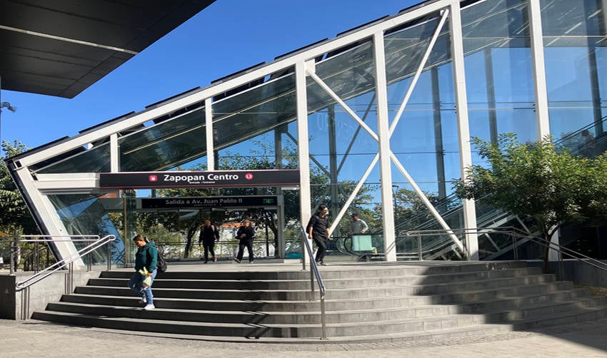 Five riders at the glass-walled exit to a light rail station in Zapopan in the Guadalajara metropolitan area.