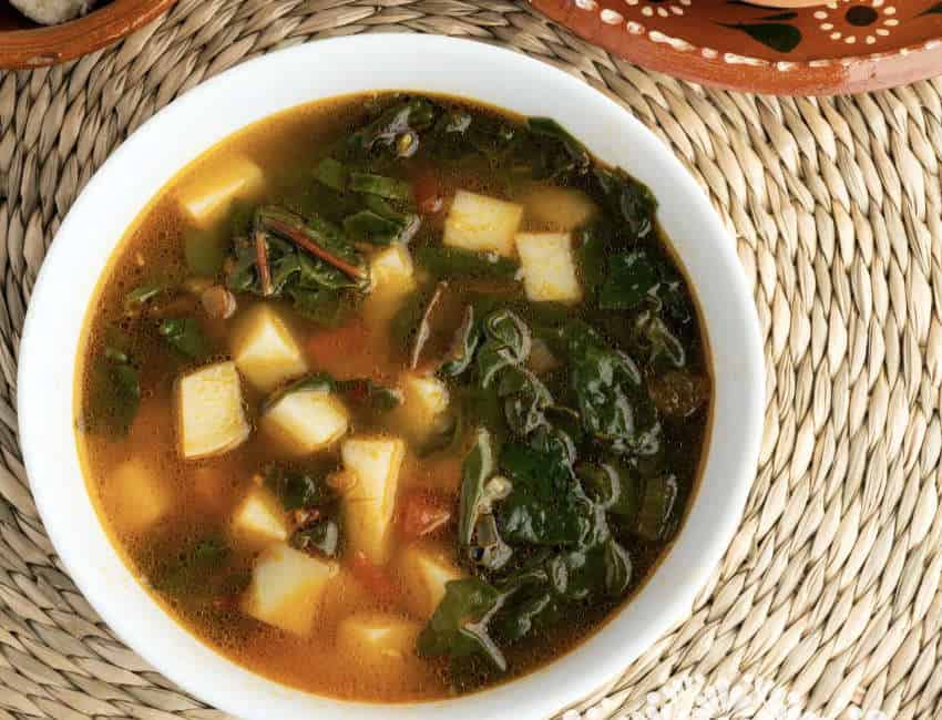 A white bowl of sopa de acelgas con papas, a traditional Swiss chard and potato soup.