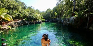 A woman sits at the edge of a Tulum cenote
