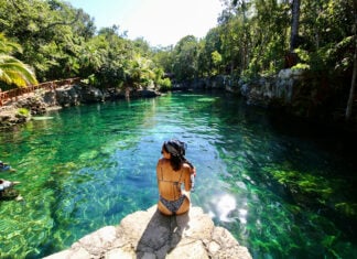A woman sits at the edge of a Tulum cenote