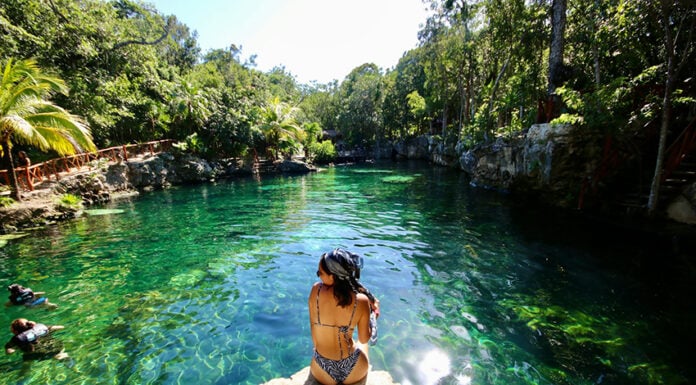 A woman sits at the edge of a Tulum cenote