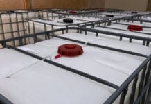 Low light view. Many large white tanks chemical packaging inside of the factory.