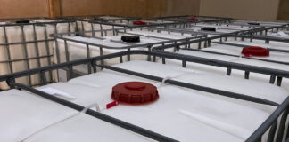 Low light view. Many large white tanks chemical packaging inside of the factory.