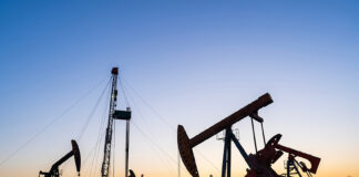 Oil pumps and a drilling rig at sunset
