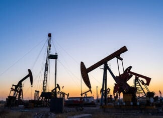 Oil pumps and a drilling rig at sunset