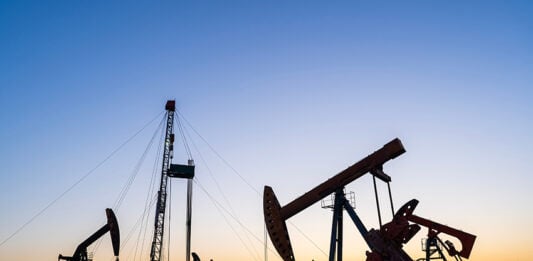 Oil pumps and a drilling rig at sunset