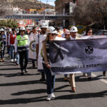 "Los mineros están en luto," reads a banner carried by a group protesting miners marching down a road
