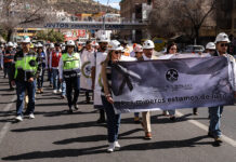 "Los mineros están en luto," reads a banner carried by a group protesting miners marching down a road