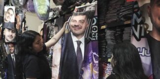 Girls look at a flannel blanket with Harfuch's face on it