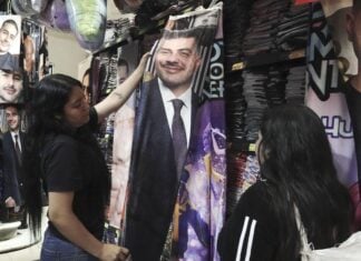 Girls look at a flannel blanket with Harfuch's face on it