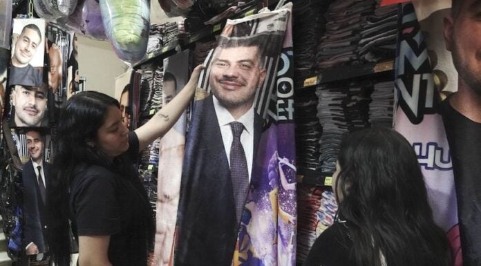 Girls look at a flannel blanket with Harfuch's face on it