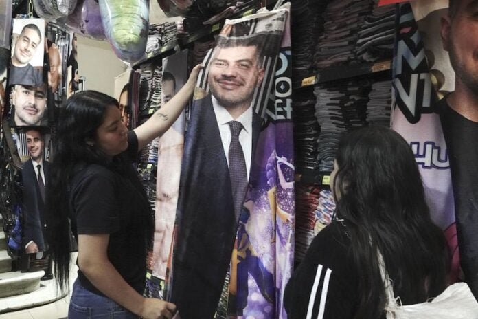 Girls look at a flannel blanket with Harfuch's face on it