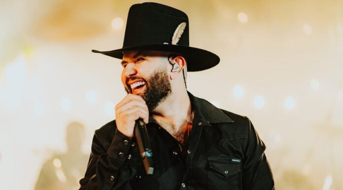 Carín León singing into a mic