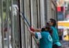 Un par de mujeres trabajan limpiando los cristales de un edificio en Paseo de la Reforma.